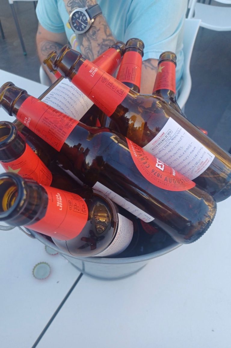 A metal bucket filled with various red and brown beer bottles.