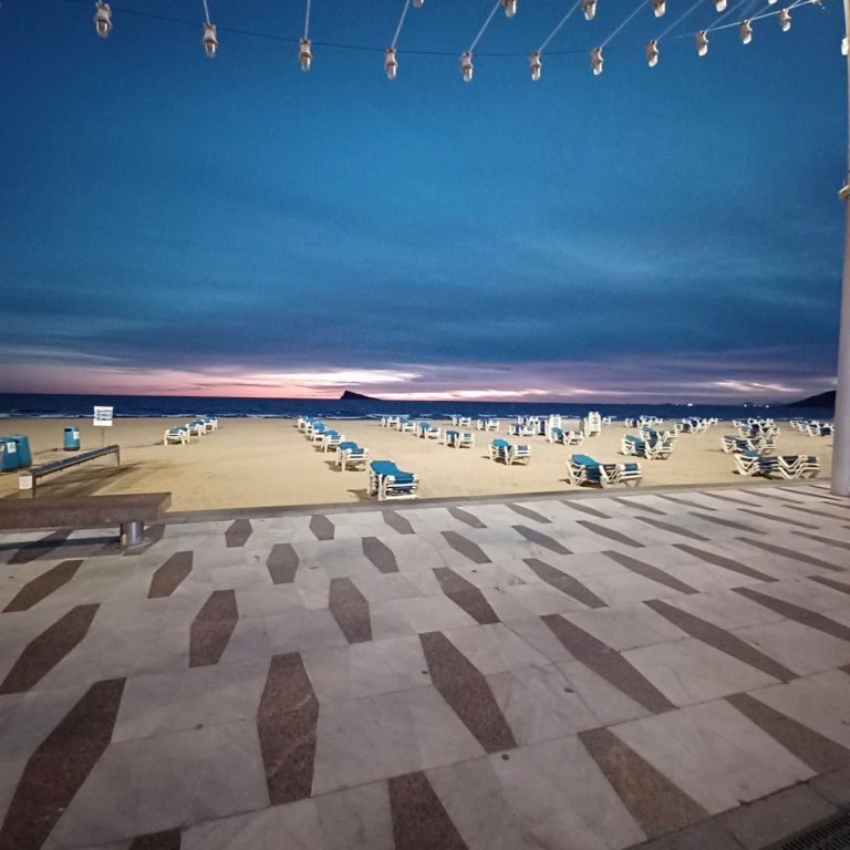 Twilight beach scene with empty deck chairs and a dusky sky.